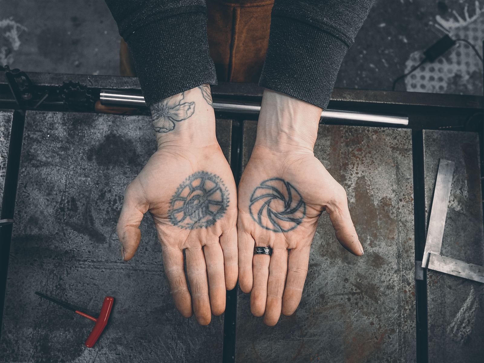 The frame builder's hands — chainring and sprocket tattoos